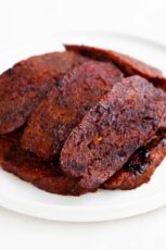 A picture of a white dish with some cooked vegan bacon slices