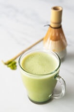 Photo of a cup of matcha latte with a bamboo whisk as decoration